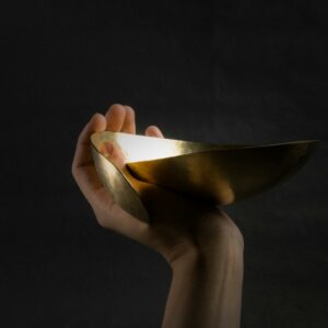 Hand holding a polished brass bowl