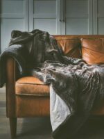 Brown leather sofa with a throw