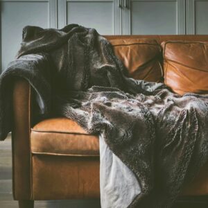 Brown leather sofa with a throw